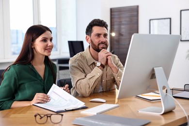 Photo of Colleagues working with computer at desk in office