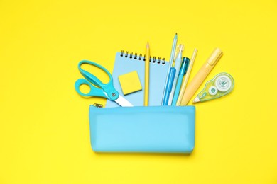 Photo of Pencil case and different stationery on yellow background, flat lay