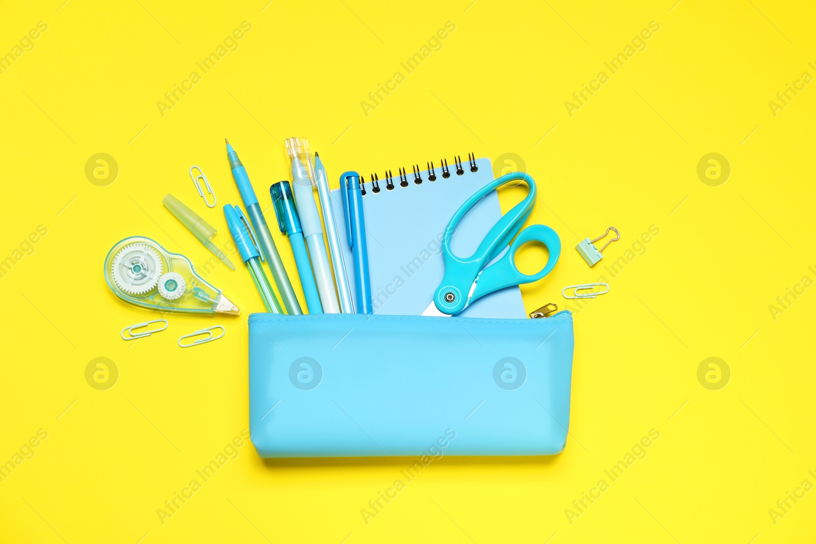Pencil case and different stationery on yellow background, flat lay Photo of Pencil case and different stationery on yellow background, flat lay