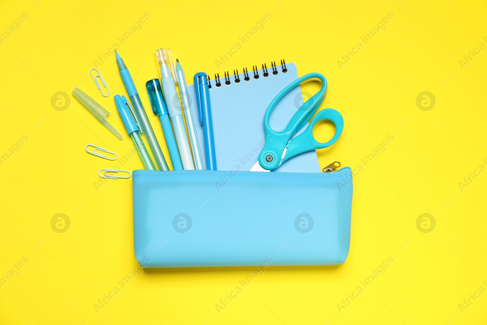 Pencil case and different stationery on yellow background, flat lay Photo of Pencil case and different stationery on yellow background, flat lay