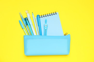 Photo of Pencil case and different stationery on yellow background, flat lay