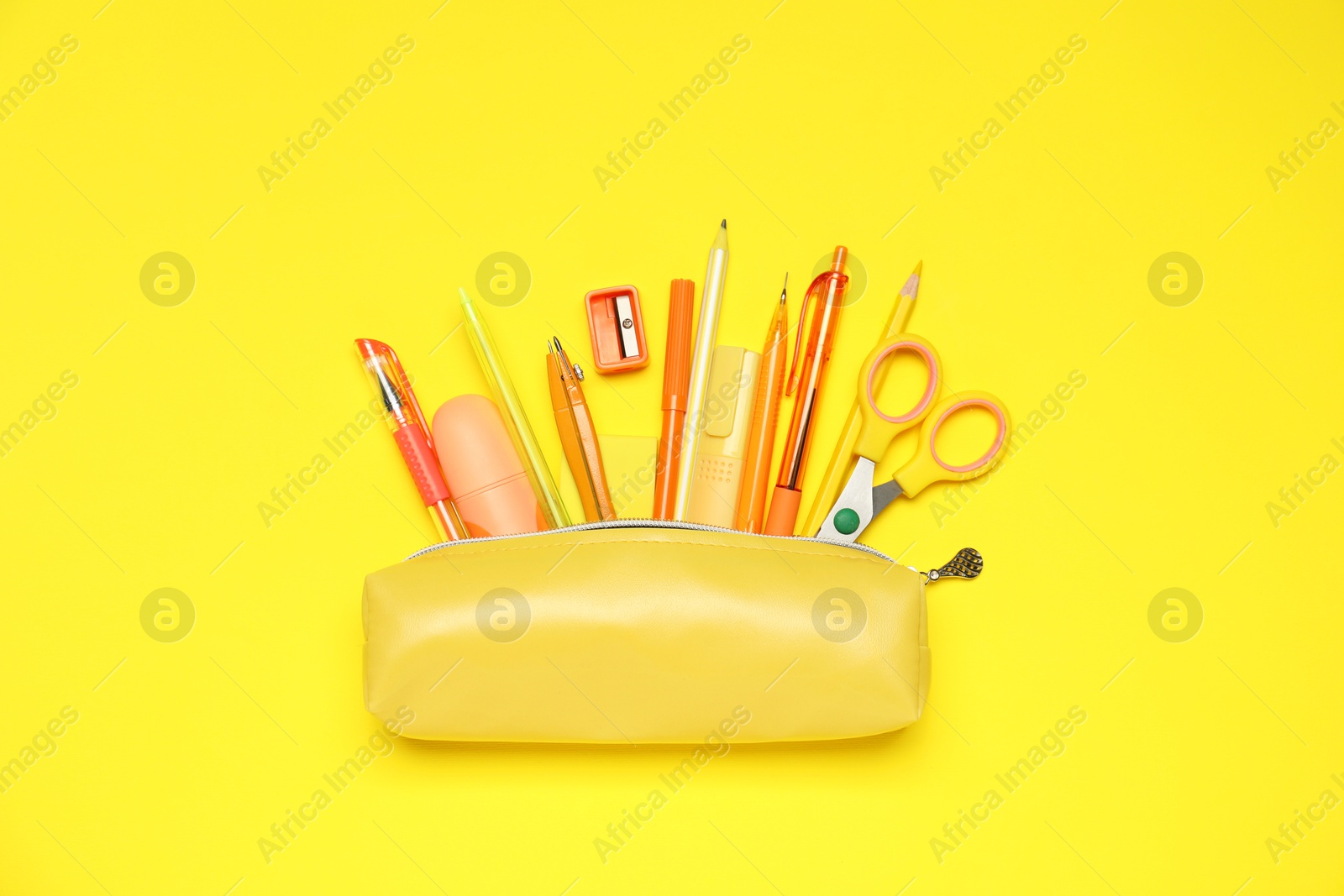 Pencil case and different stationery on yellow background, flat lay Photo of Pencil case and different stationery on yellow background, flat lay