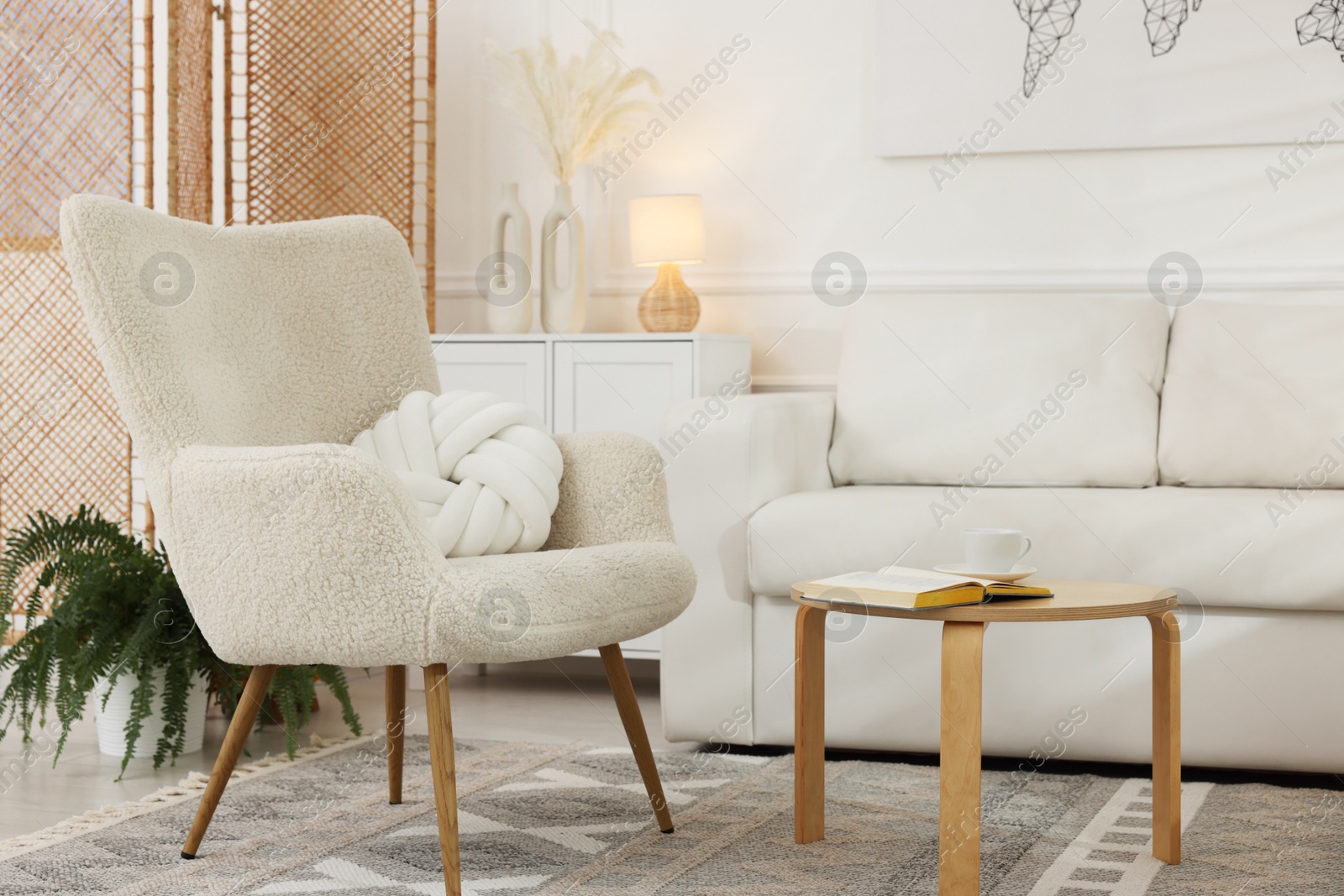 Photo of Soft armchair, coffee table, sofa and green houseplant in living room