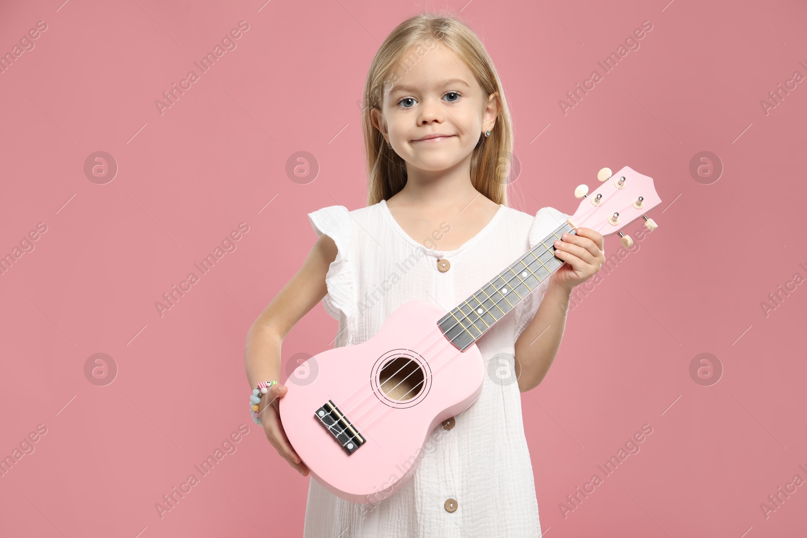 Photo of Little girl with ukulele on pink background