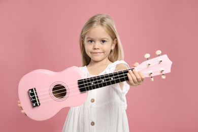 Photo of Little girl with ukulele on pink background