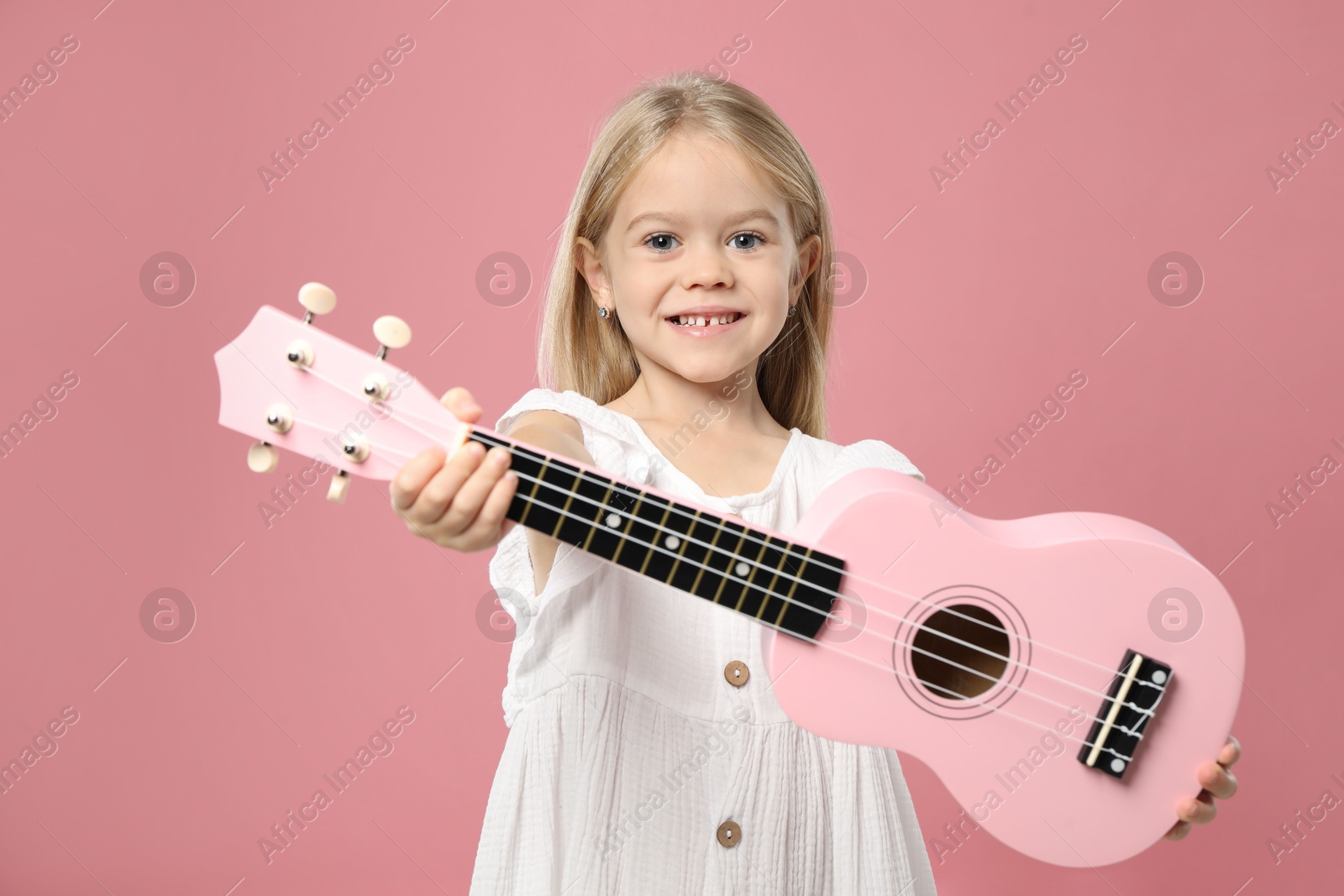 Photo of Little girl with ukulele on pink background