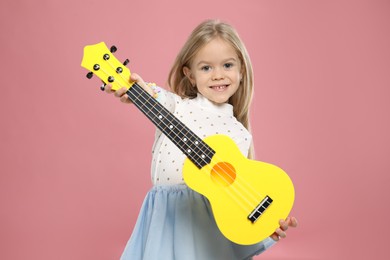 Photo of Little girl with ukulele on pink background