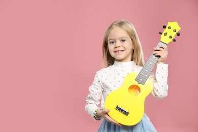 Photo of Little girl with ukulele on pink background, space for text