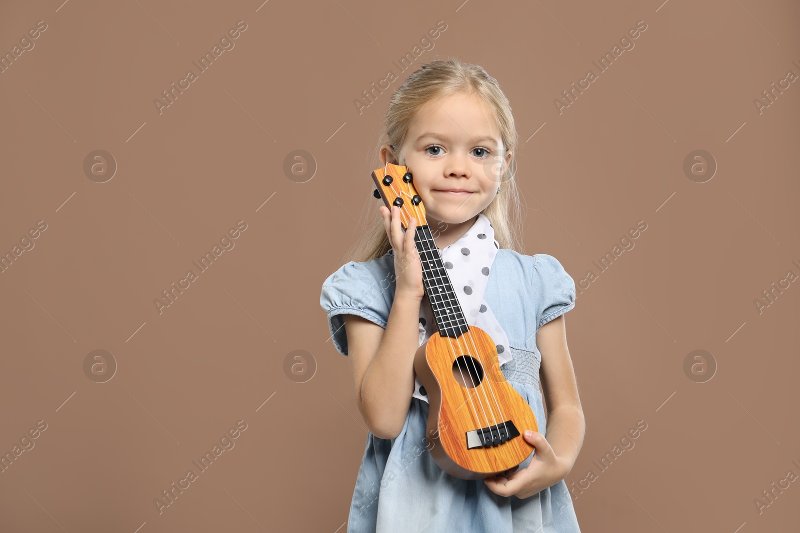 Photo of Little girl with ukulele on brown background