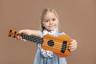 Photo of Little girl with ukulele on brown background