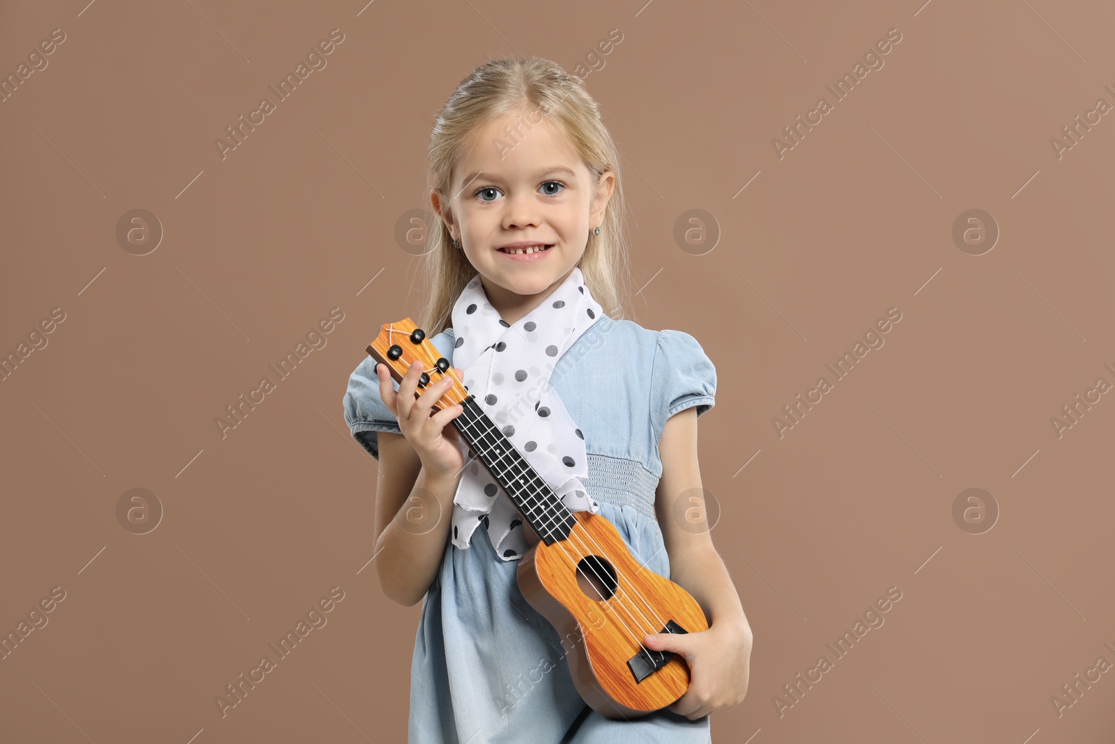 Photo of Little girl with ukulele on brown background