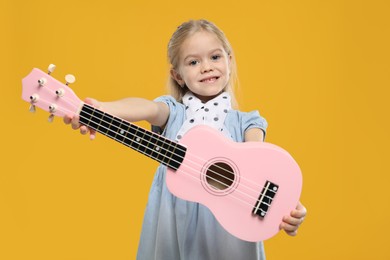 Photo of Little girl with ukulele on orange background