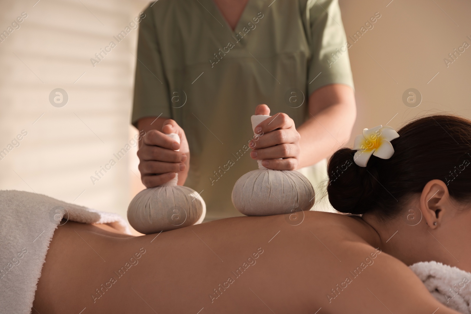 Photo of Woman receiving back massage with herbal bags in spa salon, closeup