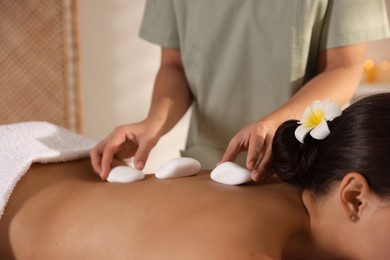 Photo of Woman receiving hot stone massage in spa salon, closeup