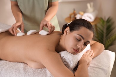 Photo of Woman receiving hot stone massage in spa salon