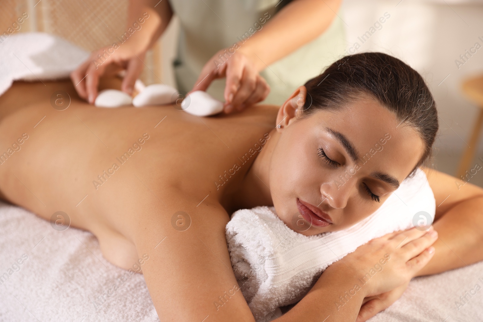 Photo of Woman receiving hot stone massage in spa salon