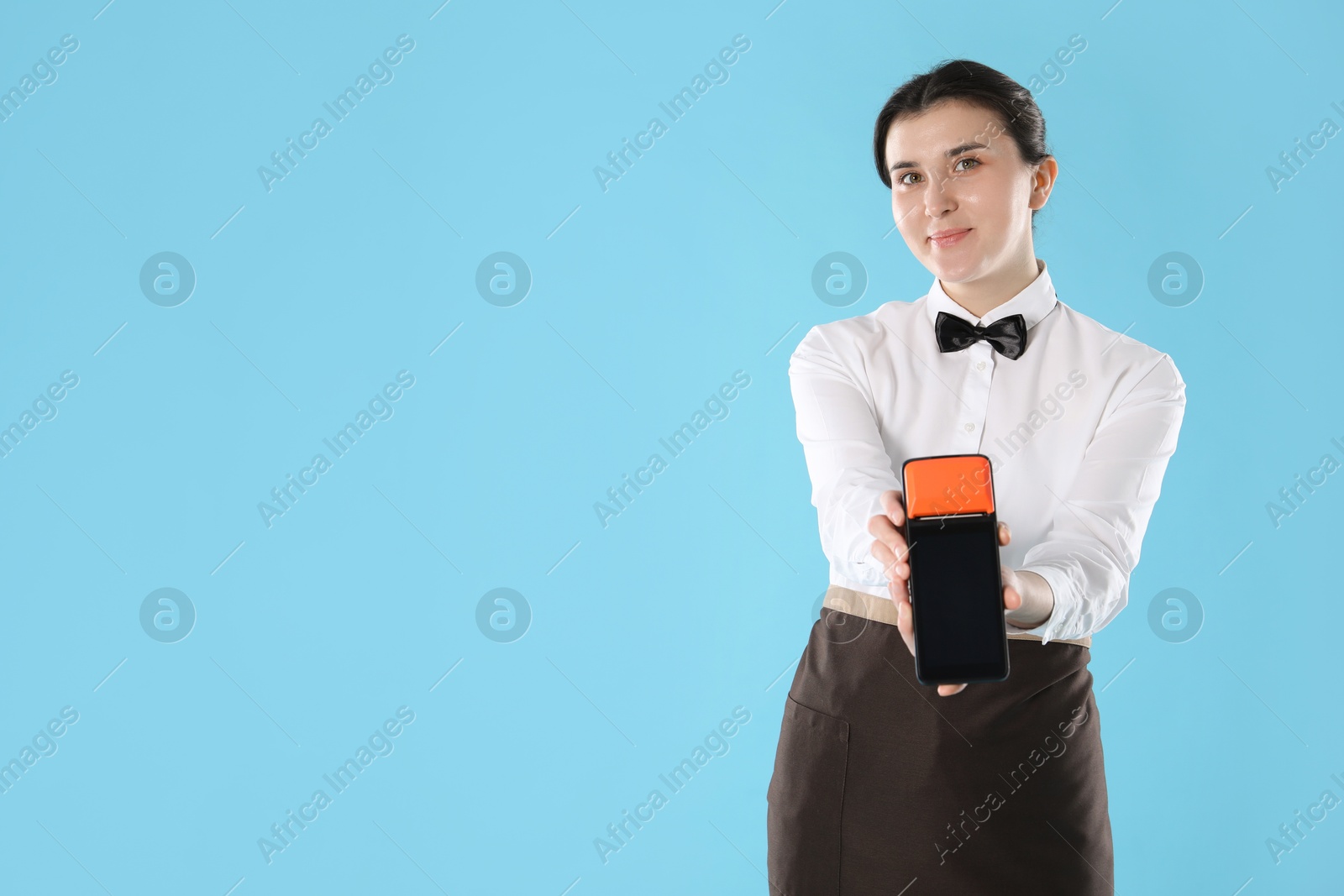 Photo of Waitress with payment terminal on light blue background, space for text