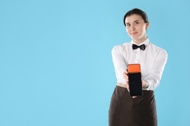 Photo of Waitress with payment terminal on light blue background, space for text