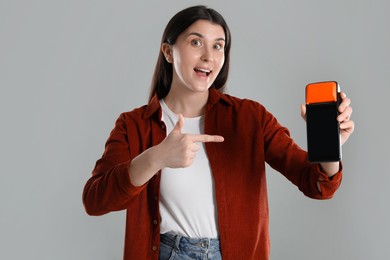 Photo of Emotional young woman with payment terminal on gray background