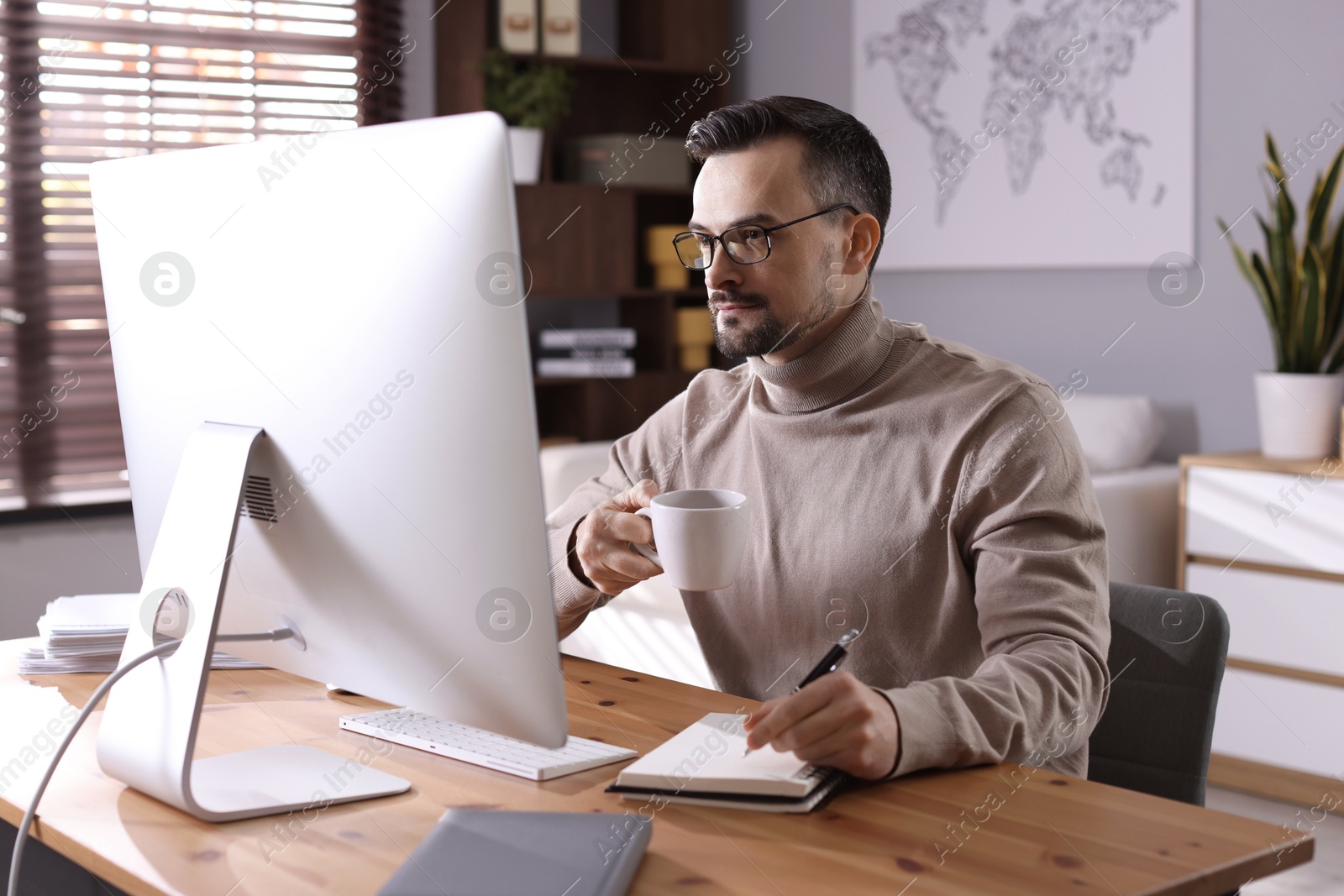 Photo of Handsome man working with computer at desk indoors. Home office