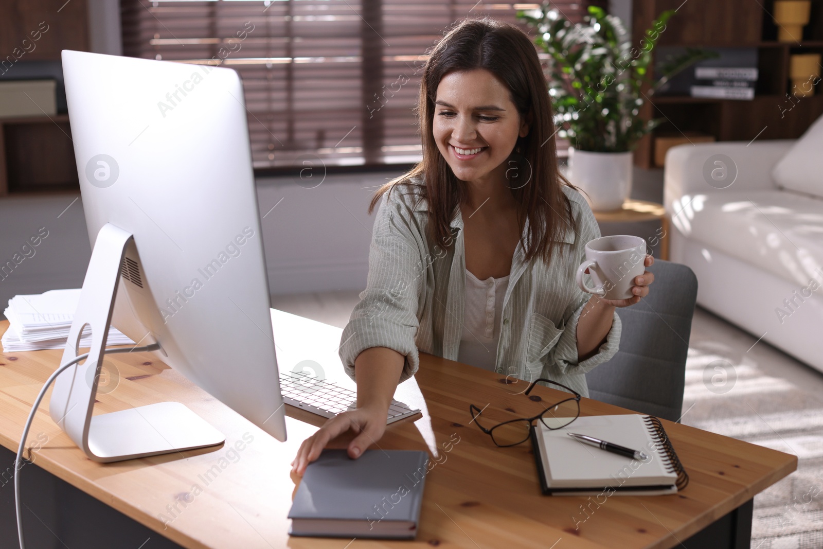 Photo of Happy woman working with computer at desk indoors. Home office