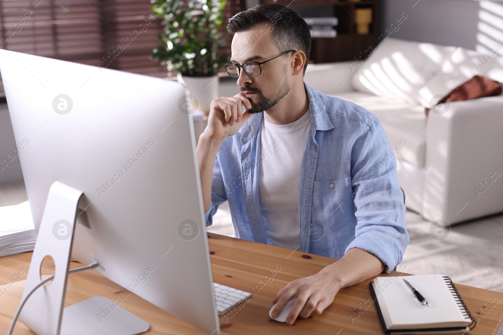 Photo of Handsome man working with computer at desk indoors. Home office