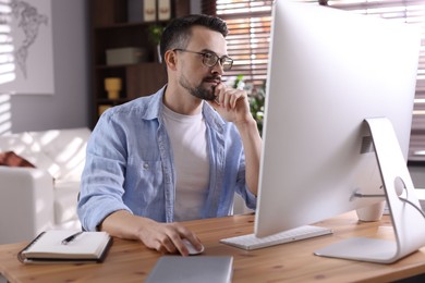 Photo of Handsome man working with computer at desk indoors. Home office