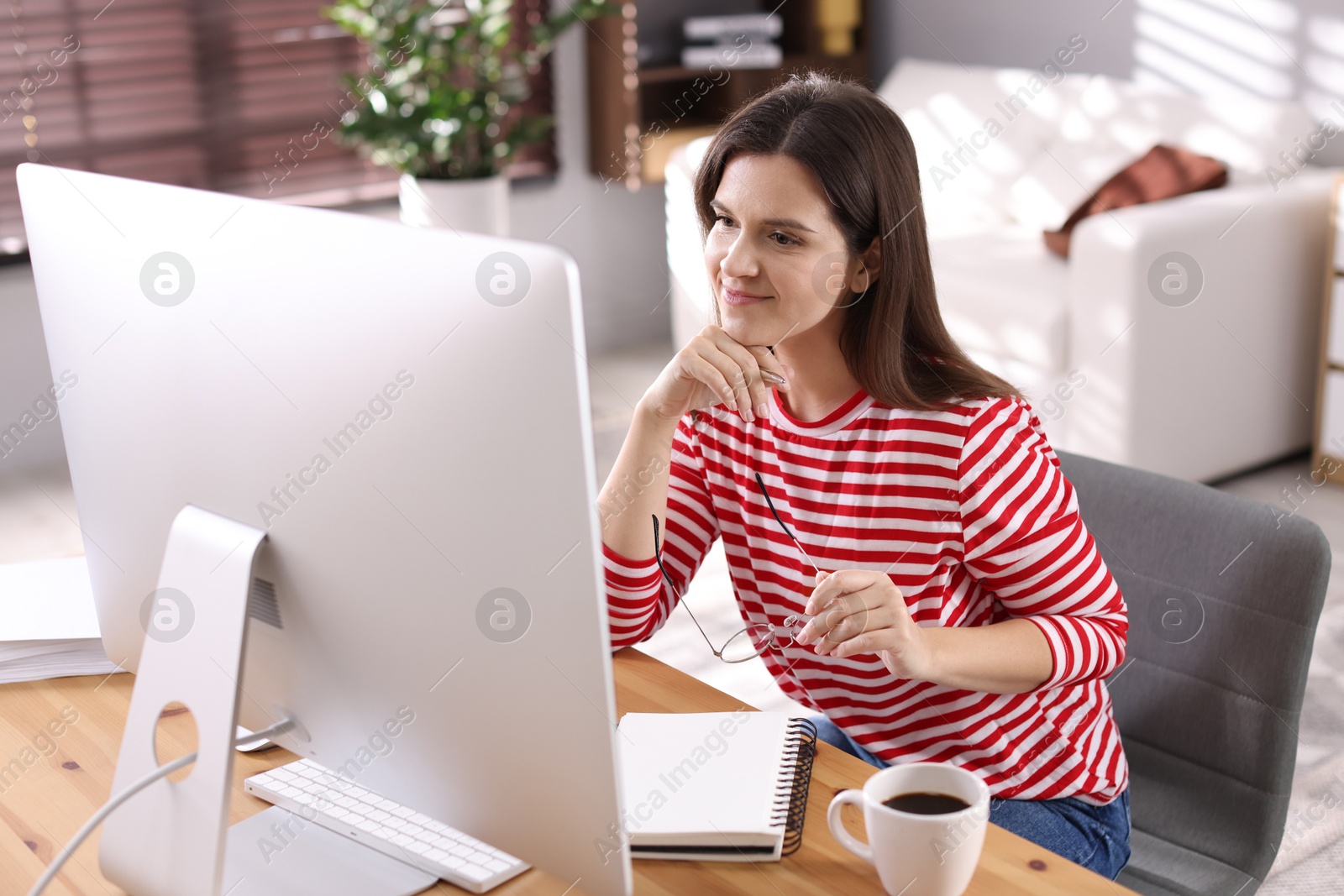 Photo of Beautiful woman working with computer at desk indoors. Home office