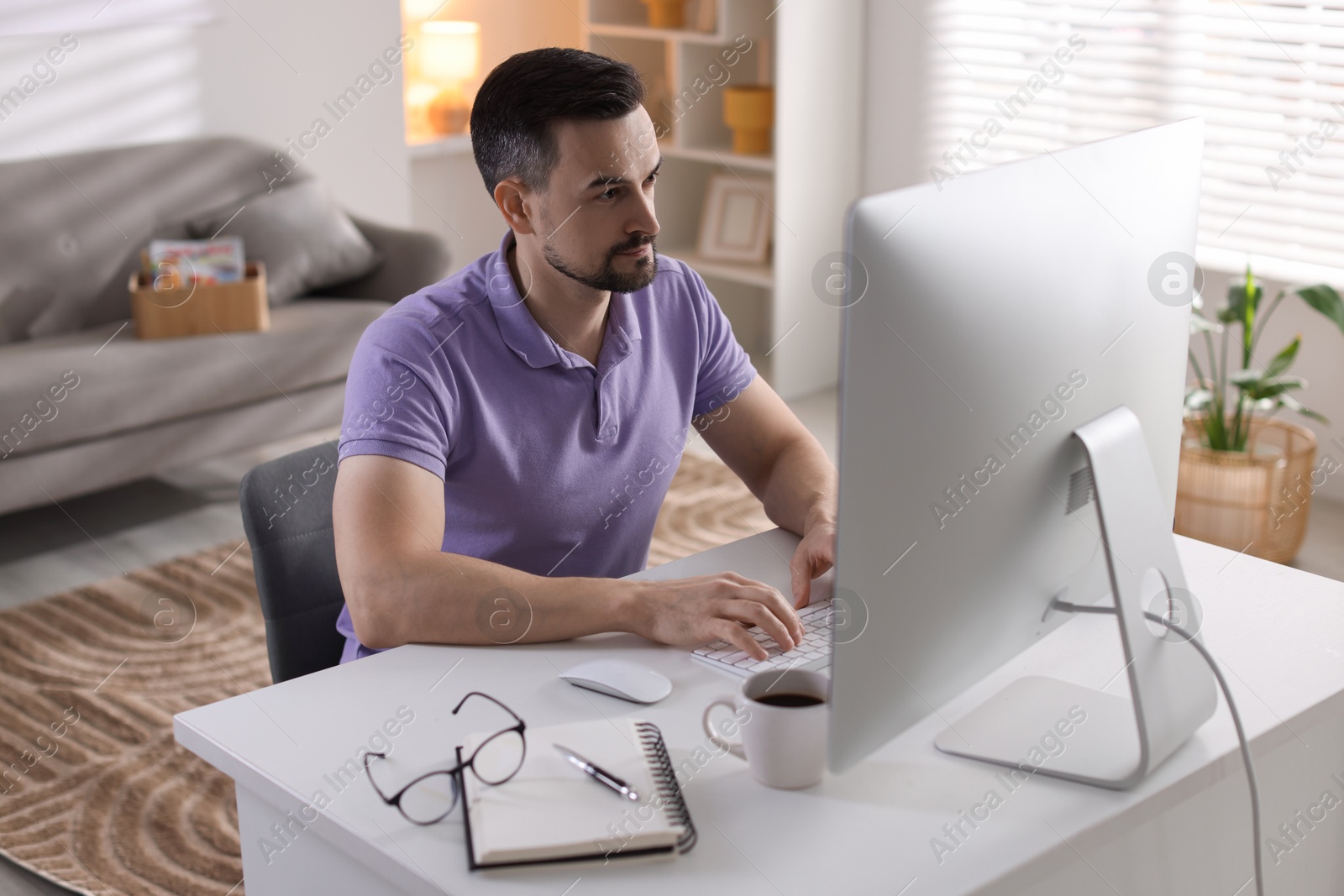 Photo of Handsome man working with computer at desk indoors. Home office