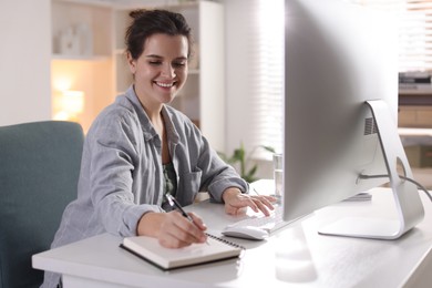 Photo of Happy woman working with computer at desk indoors. Home office