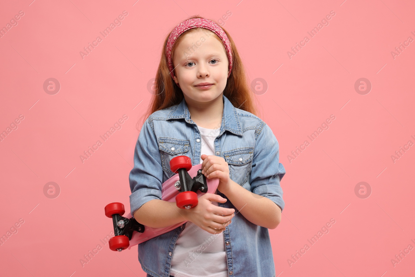 Photo of Little girl with penny board on pink background