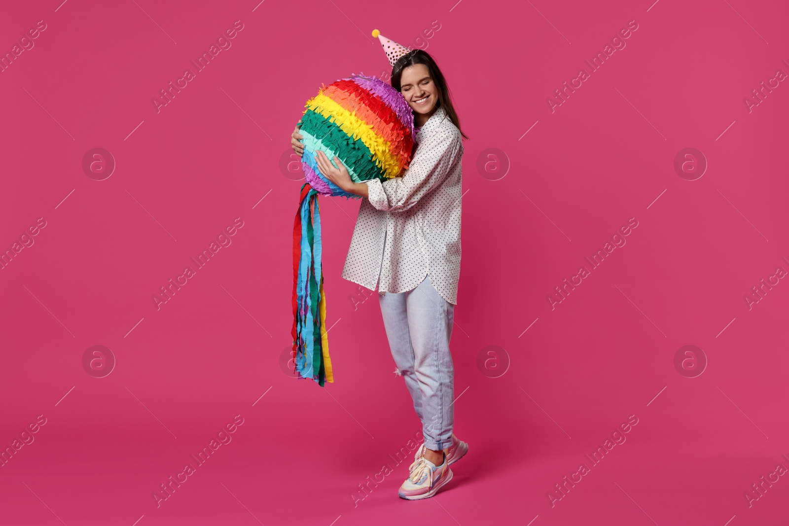 Photo of Happy woman with colorful pinata on pink background