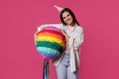 Happy woman with colorful pinata on pink background