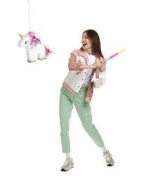 Happy woman breaking unicorn shaped pinata with stick isolated on white