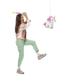 Happy woman breaking unicorn shaped pinata with stick isolated on white