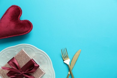 Photo of Beautiful table setting with romantic gift and heart on light blue background, flat lay. Space for text