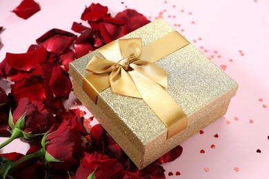 Romantic gift, roses and confetti on light pink background, closeup