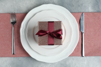 Photo of Beautiful table setting with romantic gift on grey background, flat lay