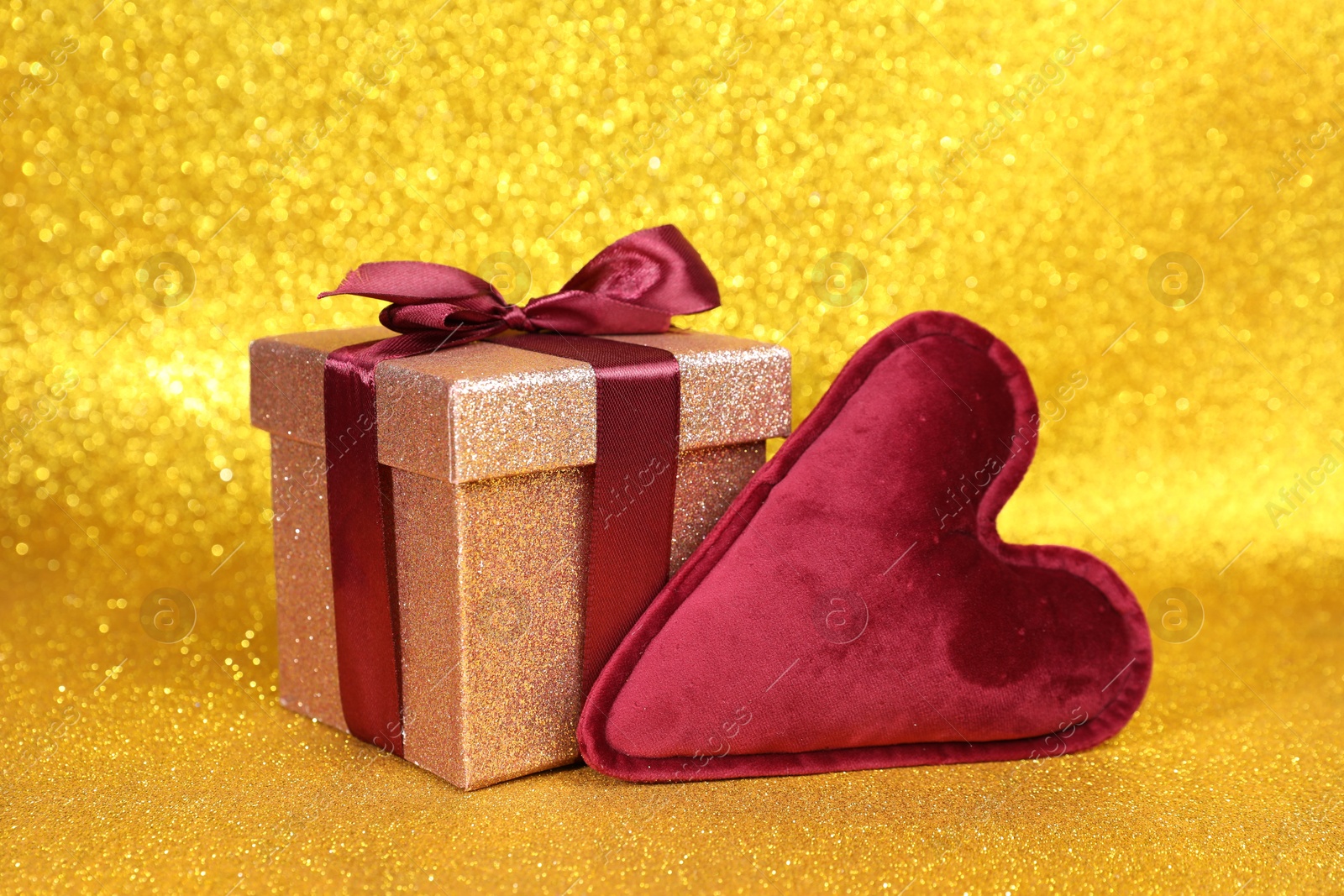 Photo of Romantic gift and heart on golden background, closeup