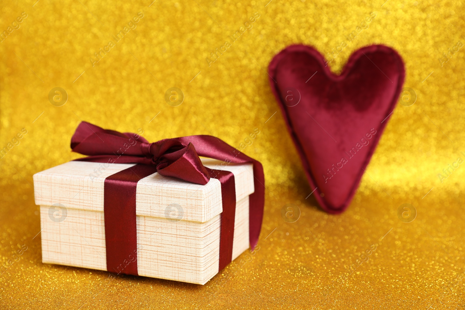 Photo of Romantic gift and heart on golden background, closeup