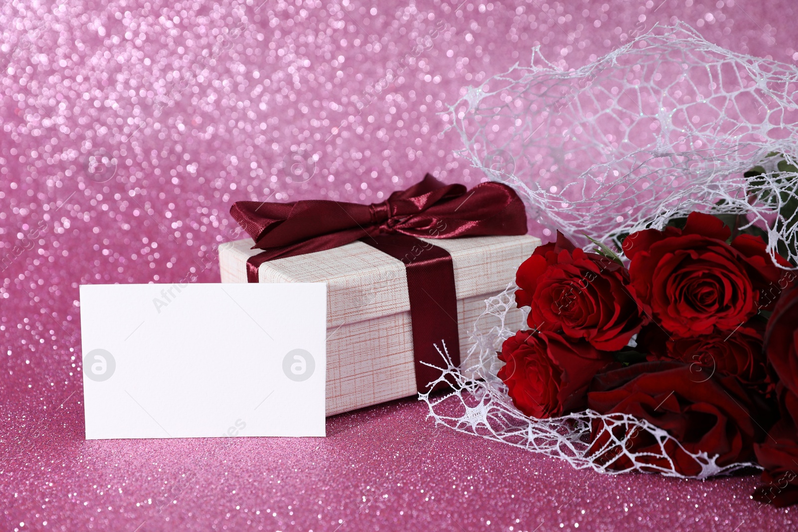 Photo of Romantic gift, blank card and roses on pink background