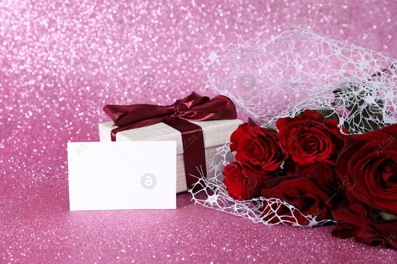 Photo of Romantic gift, blank card and roses on pink background