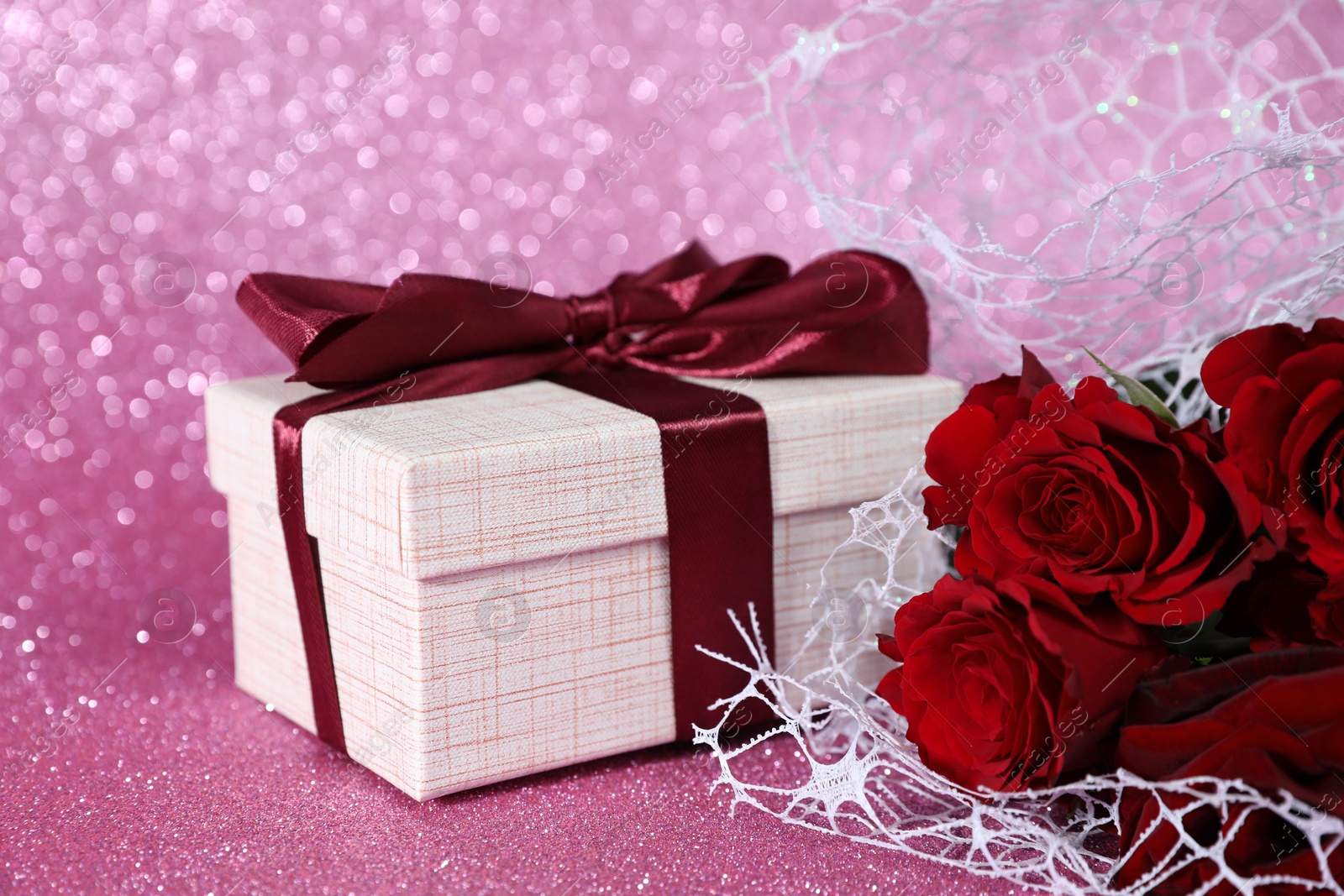 Photo of Romantic gift and roses on pink background, closeup