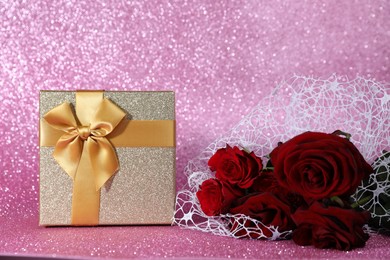 Photo of Romantic gift and roses on pink background