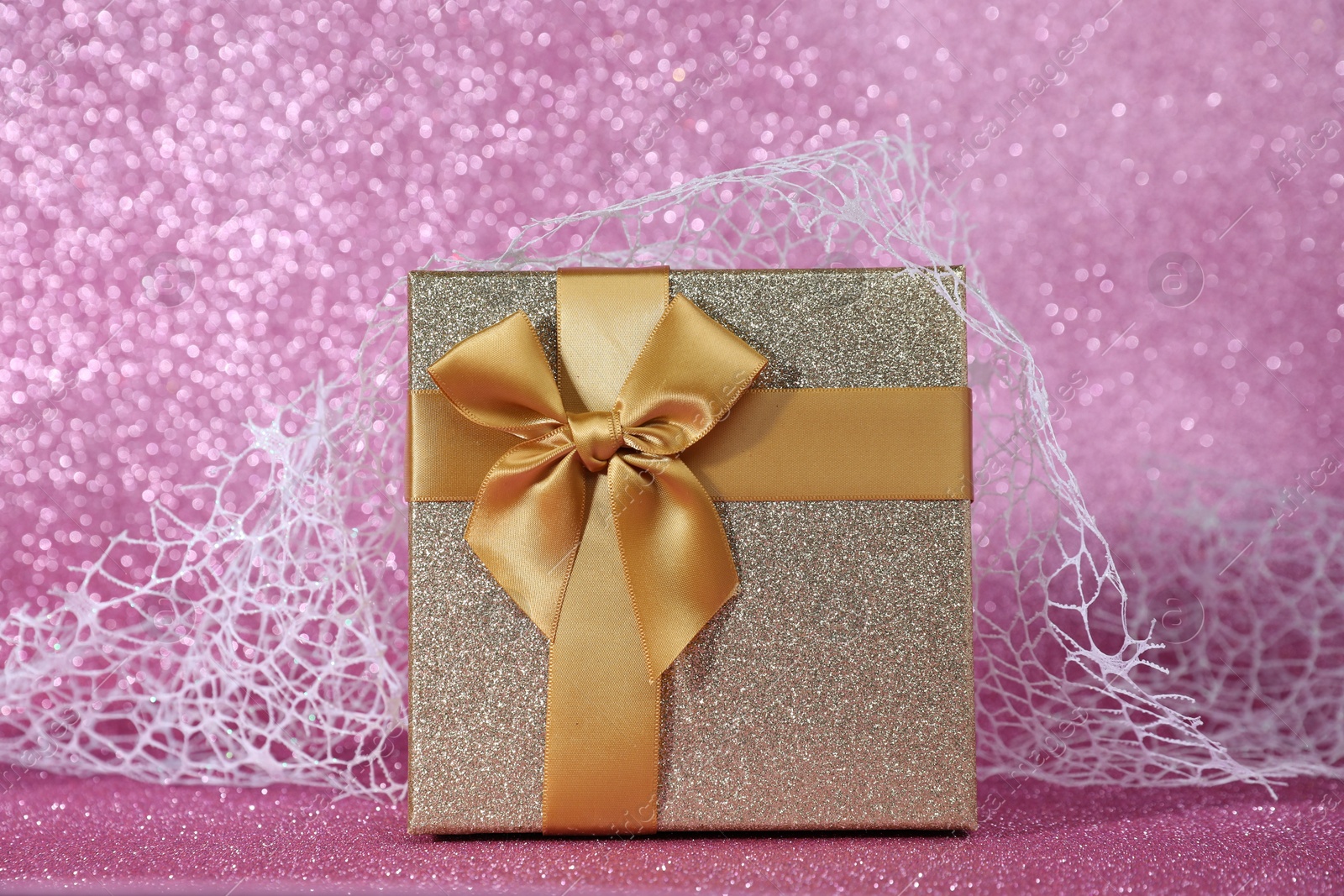 Photo of Romantic gift on pink glitter background, closeup