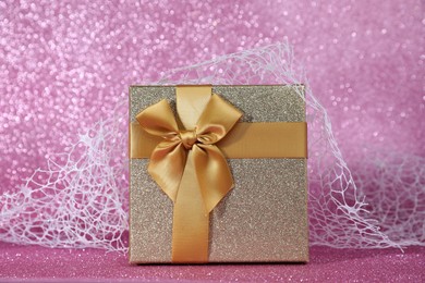 Photo of Romantic gift on pink glitter background, closeup