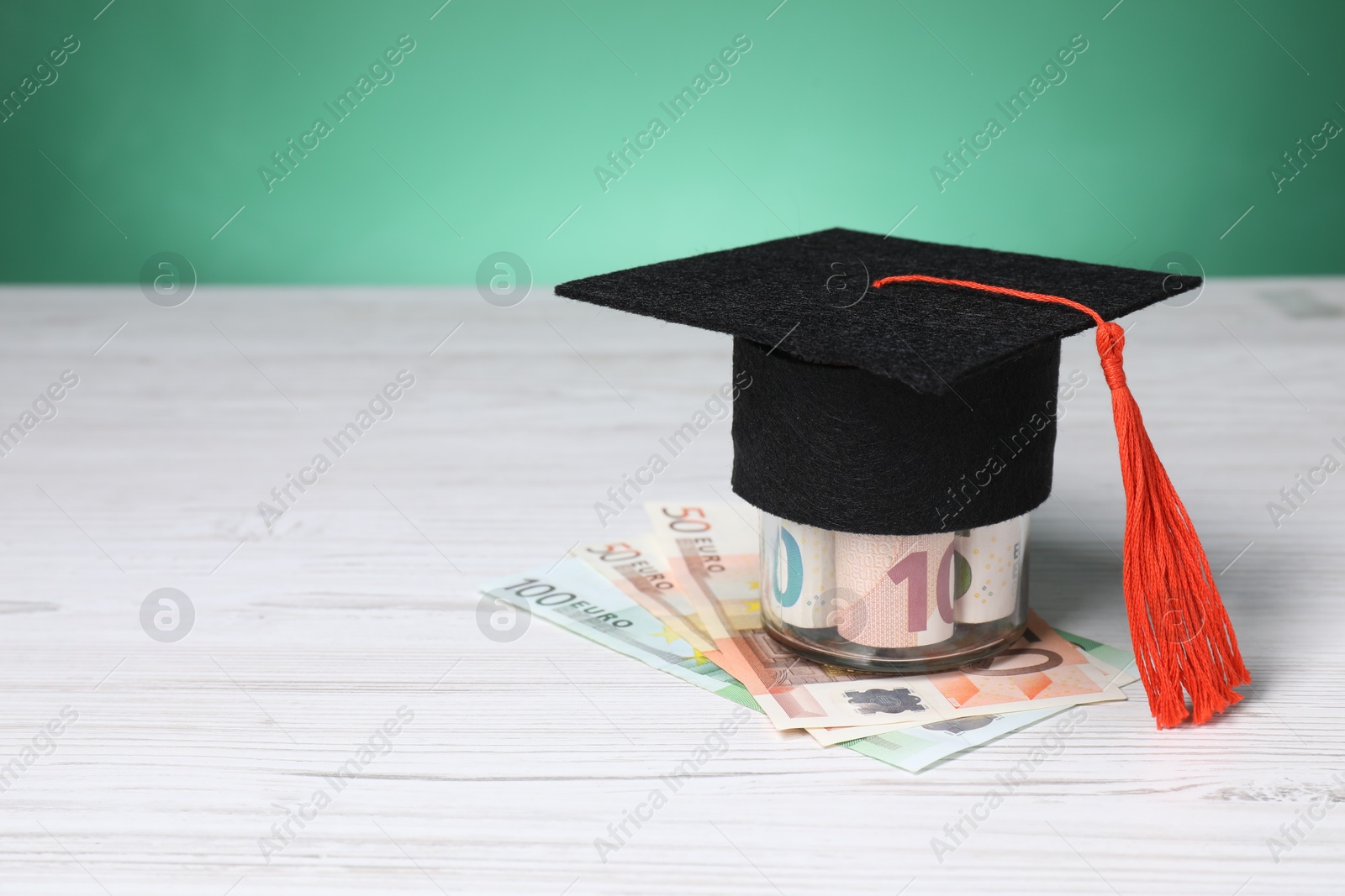 Photo of Tuition payment. Graduate hat and euro banknotes on light wooden table. Space for text