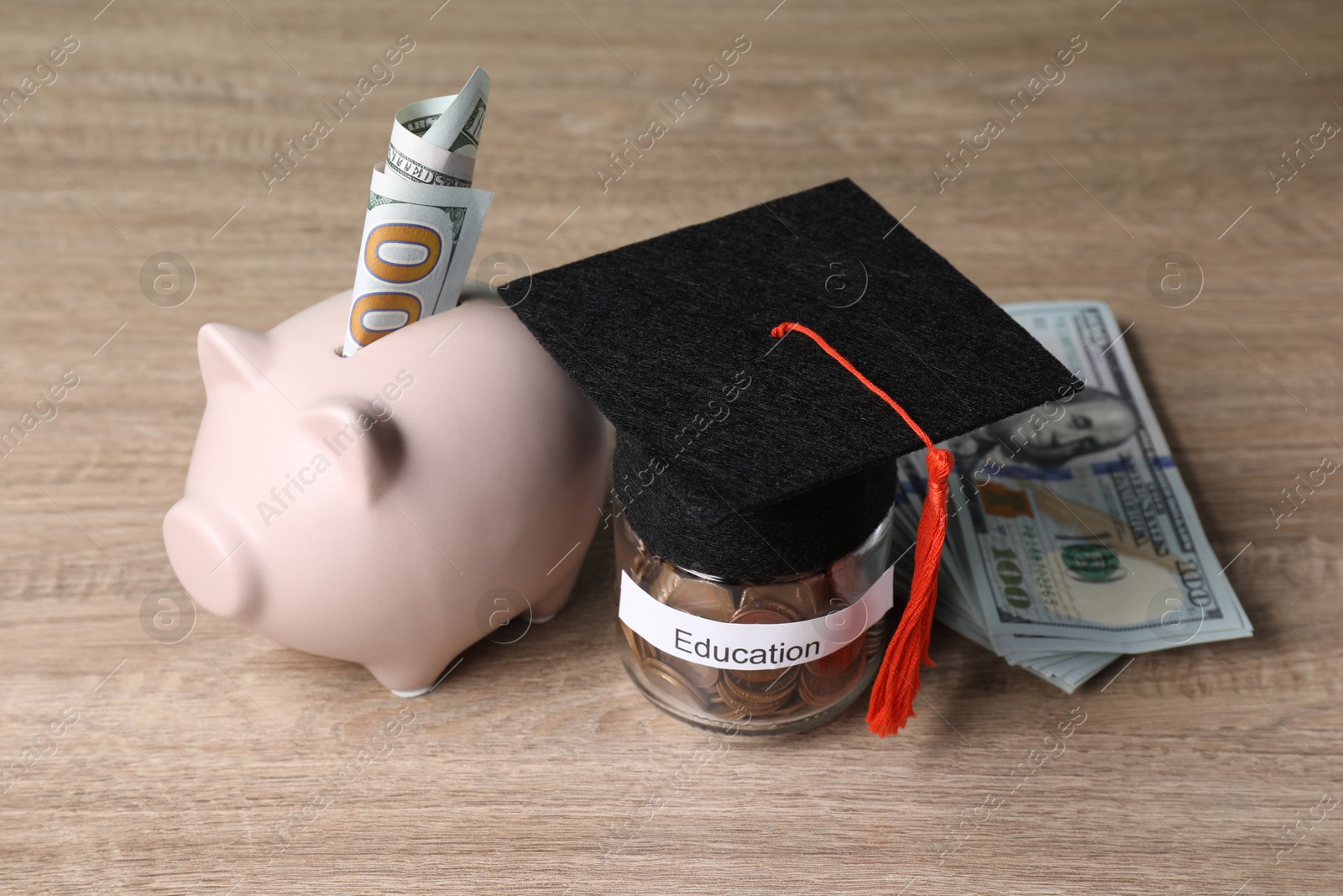 Photo of Graduate hat, dollar banknotes, piggy bank and coins in glass jar with word Education on wooden table. Tuition payment