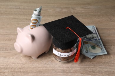 Photo of Graduate hat, dollar banknotes, piggy bank and coins in glass jar with word Education on wooden table. Tuition payment