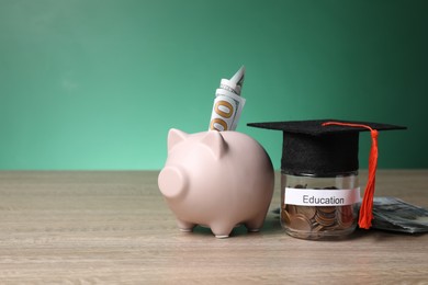 Photo of Graduate hat, dollar banknotes, piggy bank and coins in glass jar with word Education on wooden table, space for text. Tuition payment